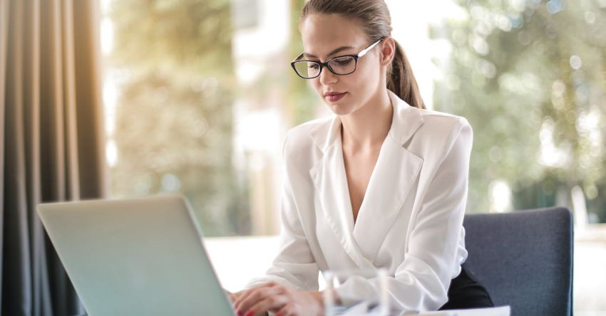 Smart Technology - Concentrated female entrepreneur typing on laptop in workplace